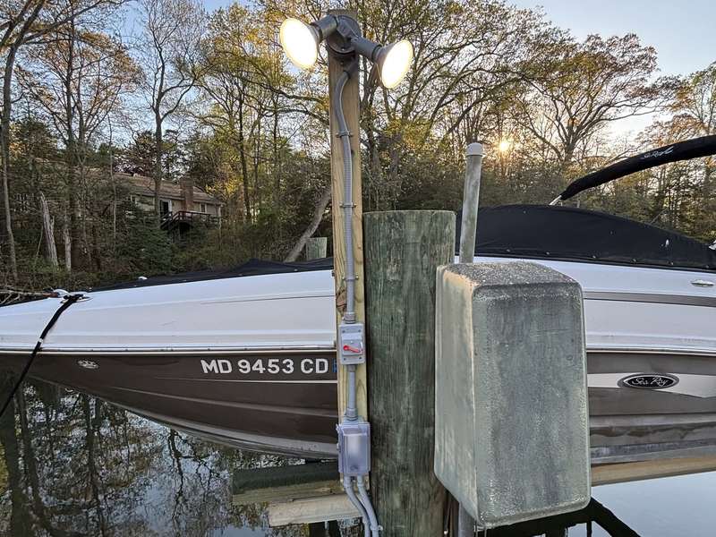 Flood lights and a weatherproof outlet on a boat dock at dusk